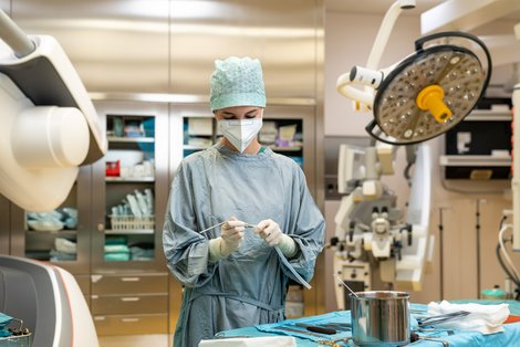 Absolventin in Schutzkleidung im OP beim Vorbereiten der Instrumente