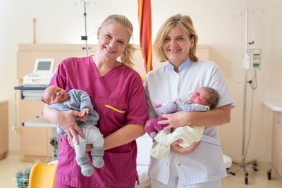 Leitende Hebamme Barbara Röblreiter und DGKP Margit Steininger mit 2 Babys im Arm