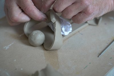 Hände die aus Ton eine Figur formen