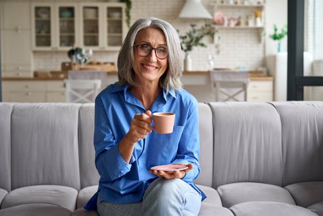 Frau sitzt mit Kaffeetasse auf Sofa
