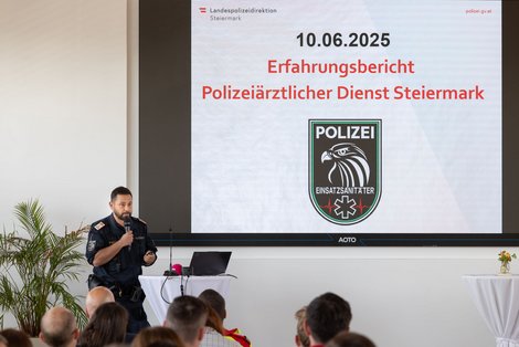 Vortragender vor Leinwand mit Mikrofon in der Hand