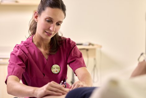 Eva-Maria Eckerstorfer massiert in einem den Bauch einer schwangeren Person.