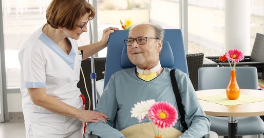 Mitarbeiterin mit Patient im Rollstuhl