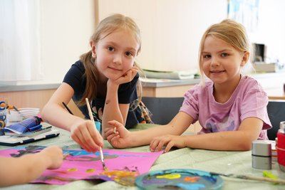 Zwei Kinder malen an einem Tisch gemeinsam ein Bild.