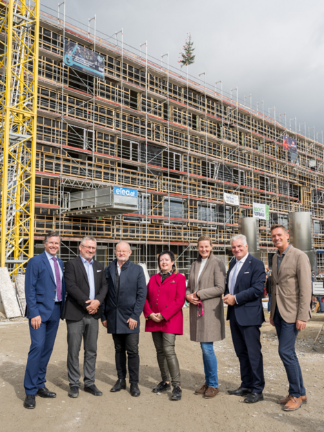 Gruppenfoto vor Rohbau mit Bäumchen am Dach