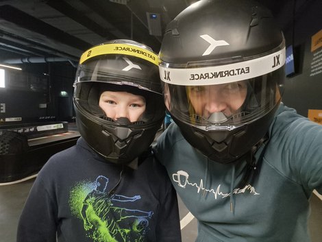 Stephan Famler und sein Sohn mit Rennhelmen auf einer Indoor-Kartbahn.