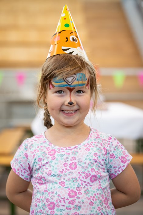 Bunt geschminktes Kind mit Partyhut