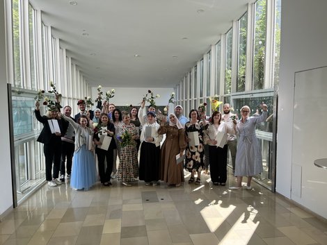 Gruppenfoto der AbsolventInnen mit Rosen und Diplomen