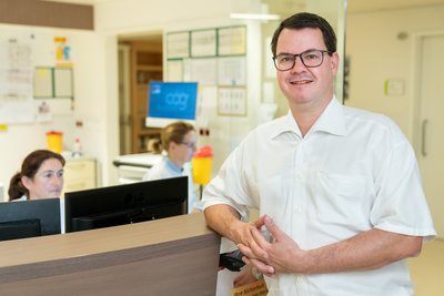 Arzt beim Stationsstützpunkt mit Mitarbeiterinnen im Hintergrund