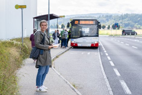 Frau wartet an der Bushaltestelle vor dem Salzkammergut Klinikum Vöcklabruck