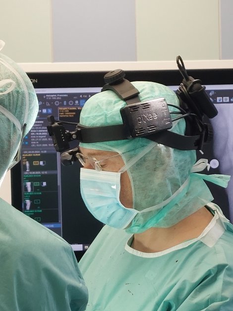 Chirurg in Schutzkleidung mit Kamera am Kopf