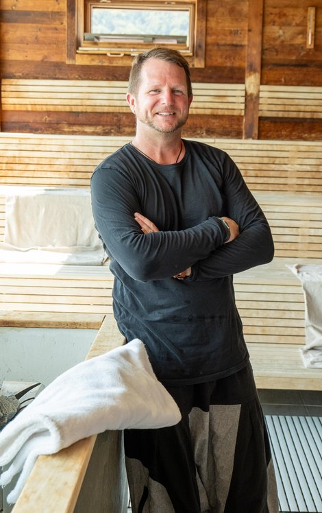 Michael Kerschhofer in einer Sauna, die Arme verschränkt.