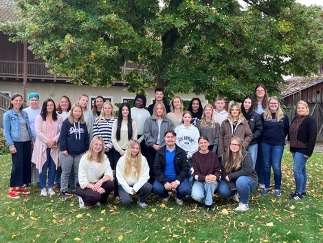 Gruppenfoto Auszubildende in einer Wiese vor einem Baum
