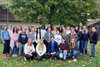 Gruppenfoto Auszubildende in einer Wiese vor einem Baum
