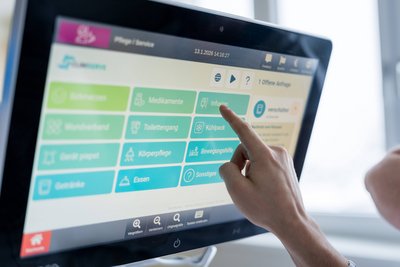 PatientIn tippt auf Bildschirm am Krankenbett