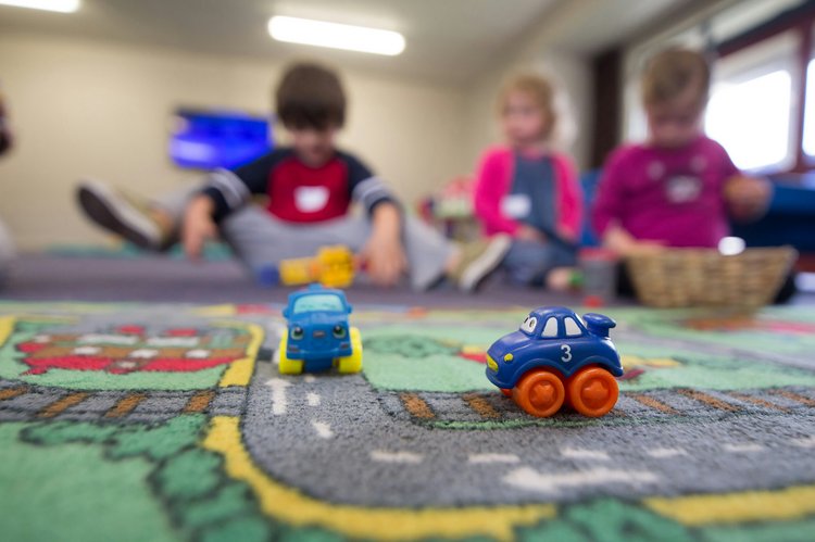 Spielzeug Autos auf einem Spieleteppich - 3 Kinder unscharf im Hintergrund