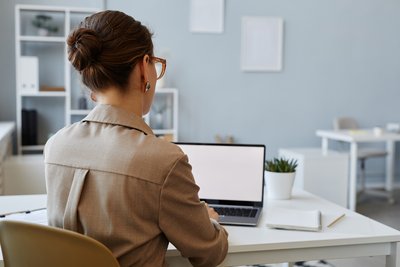 Frau am Bildschirm sitzend. Stundenlanges Sitzen erhöht das Risiko einer Thrombose 