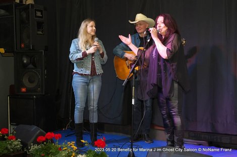 Andrea Nußbaumer singt auf einer Bühne mit einer weiteren Sängerin und einem Gitarristen