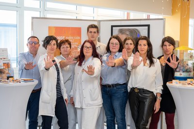 Gruppenfoto und alle halten - als Stopp-Zeichen - die Hand Richtung Kamera