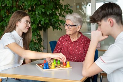 Zwei PflegestarterInnen beim spielen mit einer Seniorenheim Bewohnerin