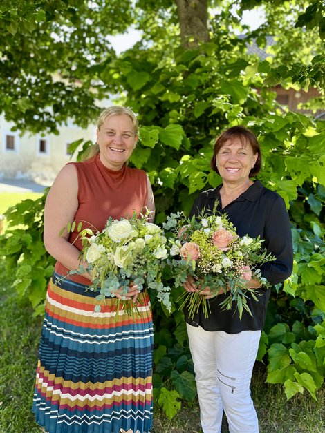 Beide Frauen halten Blumensträuße in den Händen