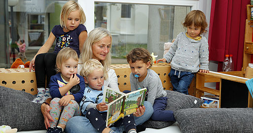 Kinderbetreuerin liest ein Buch vor.