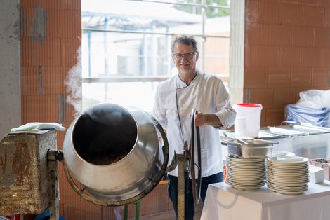 Küchenleiter mit Gulasch in der Mischmaschine