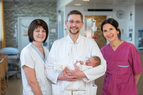 Das Team der Geburtshilfe am Klinikum Schärding - v.l.n.r. Krankenpflegerin, Arzt und Hebamme, Arzt hält Baby im Arm