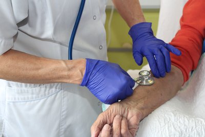 Arzt oder Pfleger hält Stethoskop an Arm