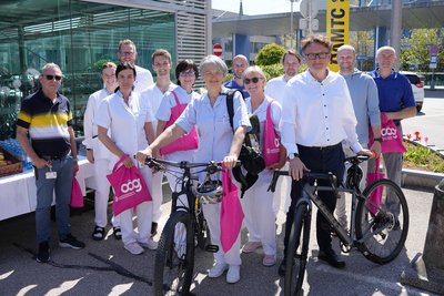 Gruppe von MitarbeiterInnen mit Fahrrädern vor gläsener Fahrradgarage