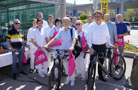 Gruppe von MitarbeiterInnen mit Fahrrädern vor gläsener Fahrradgarage
