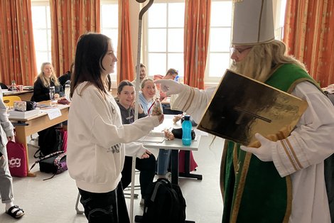 Der Nikolaus übergibt ein Geschenk an eine Auszubildende