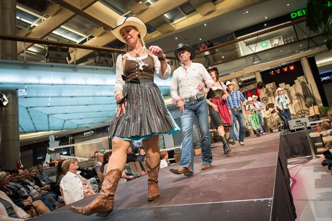 Sylvia Hollnsteiner mit anderen TänzerInnen in Dirndl, Cowboy Hut und Boots bei einem Auftritt in einem Einkaufszentrum