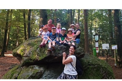 Kinder sitzen im Wald auf einem bemoosten Felsen