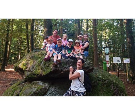 Kinder sitzen im Wald auf einem bemoosten Felsen