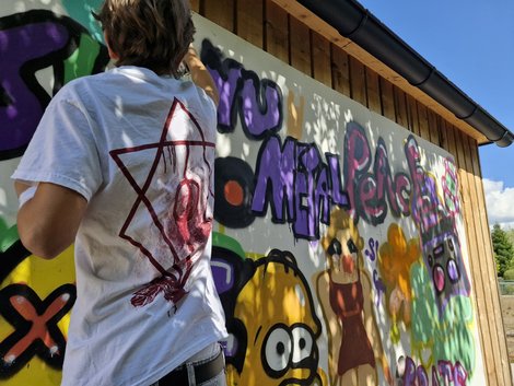 Junger Mann von hinten, der gerade ein Grafitti sprayed
