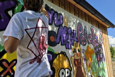Junger Mann von hinten, der gerade ein Grafitti sprayed