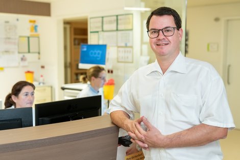 Arzt lehnt am Empfang einer Krankenhausstation