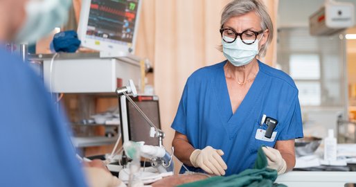 Pflegerin an einem Intensivbett mit beatmetem Patienten