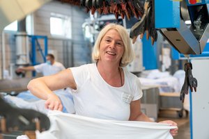 Foto einer Mitarbeiterin bei der Arbeit in der Wäscherei