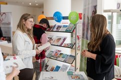 Eine Besucherin und eine Frau an einem Selbsthilfestand unterhalten sich im Kepler Uniklinikum über das Selbsthilfeangebot