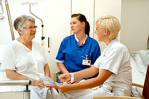 Schülerin und Krankenpflegerin im Gespräch mit einer Patientin