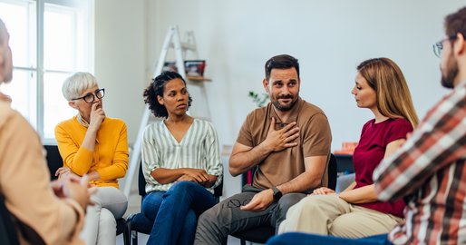 verschiedene Personen sitzen im Kreis und reden miteinander