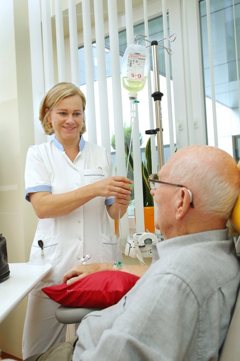 Pflegekraft justiert Infusion von Patient