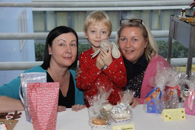 Zwei Frauen mit einem Kind in der Mitte und selbstgebastelten Geschenken am Tisch