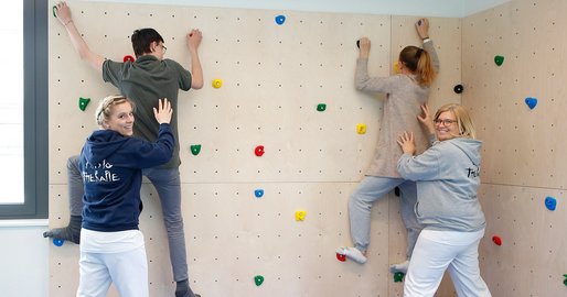 2 Therapeutinnen geben 2 PatientInnen Hilfestellung an der Kletterwand