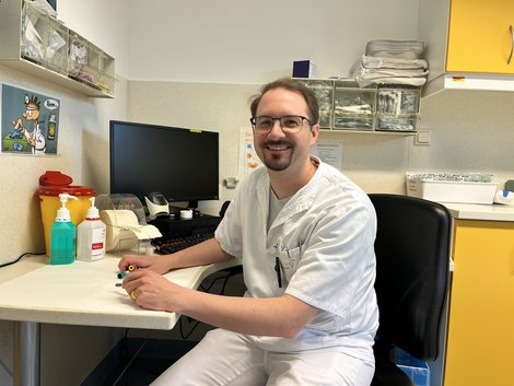 Radiologietechnologe Harald Brunner sitzt an einem Arbeitsplatz mit medizinischer Ausstattung und Bildschirm
