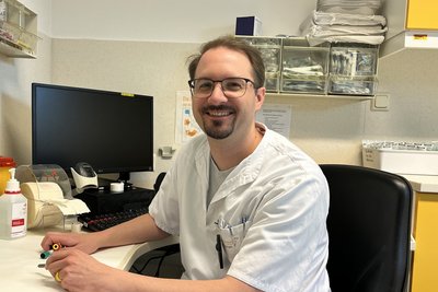 Radiologietechnologe Harald Brunner sitzt an einem Arbeitsplatz mit medizinischer Ausstattung und Bildschirm