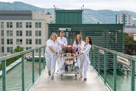 JungärztInnen bringen Transportliege zum Hubschrauberlandeplatz des KUK