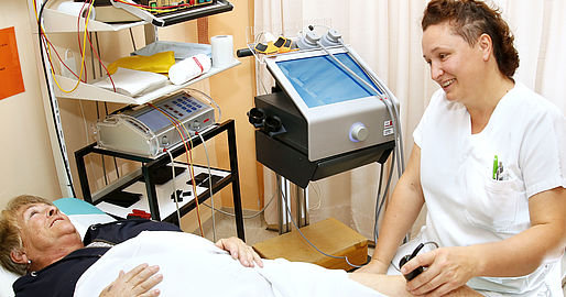 Therapeutin bei der Elektrotherapie des Knies einer Patientin